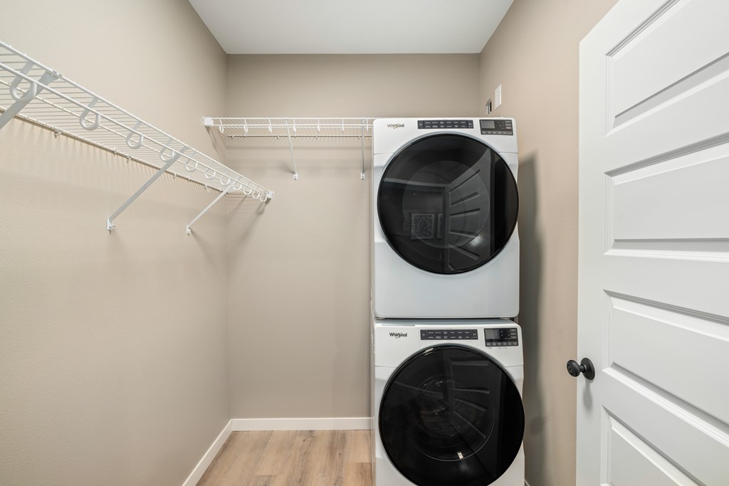 A white dryer and washer are stacked on top of each other in a laundry room.