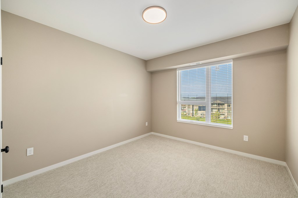 A room with a window and a carpeted floor.