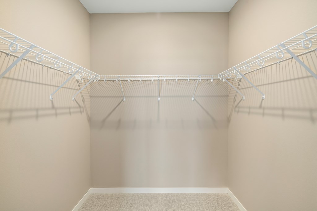 Empty white walk in closet with shelves.