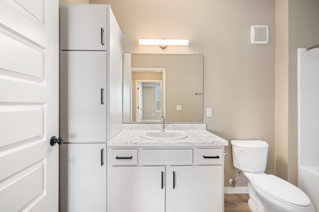 A white bathroom with a sink, toilet, and medicine cabinet.