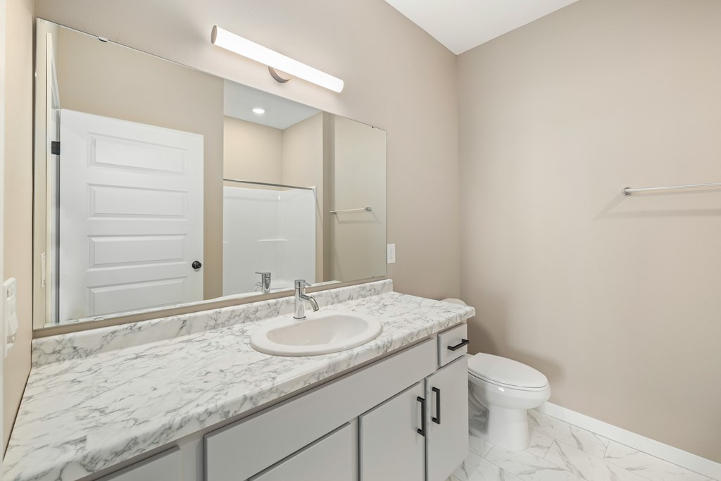 A bathroom with a marble countertop and a white toilet.