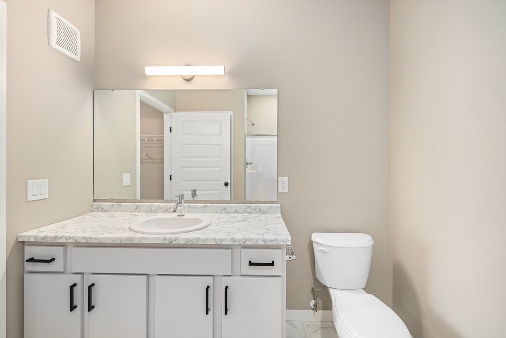 A bathroom with a marble countertop and white fixtures.