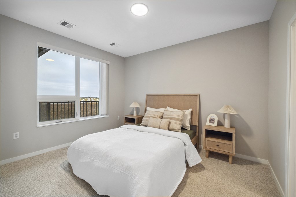 a white bedroom with a large window and a bed