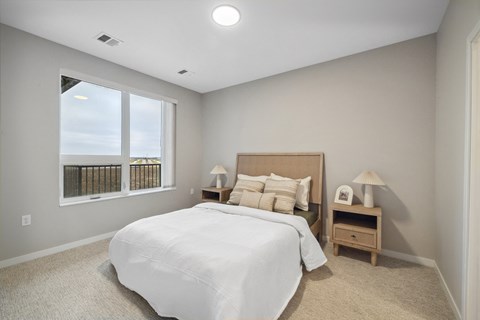 a white bedroom with a large window and a bed