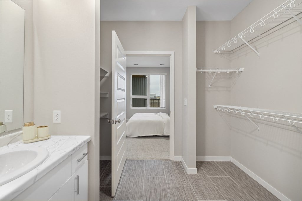 a bathroom with a sink and a mirror and a walk in closet