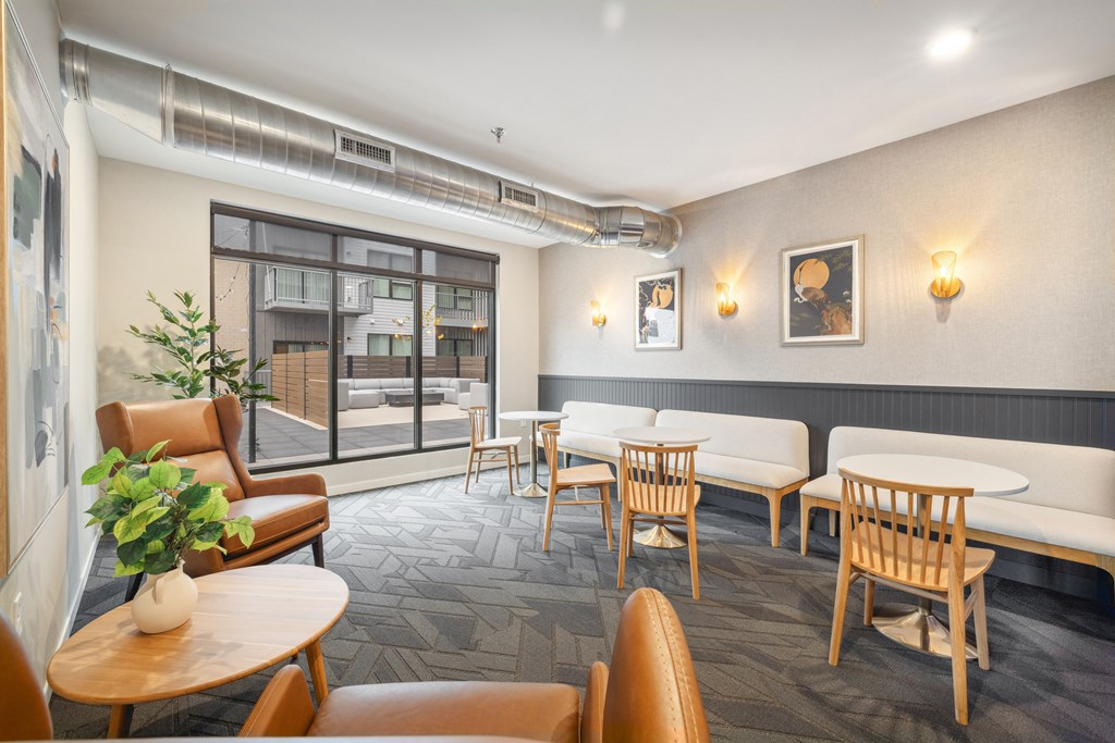 a lounge area with tables and chairs and a large window