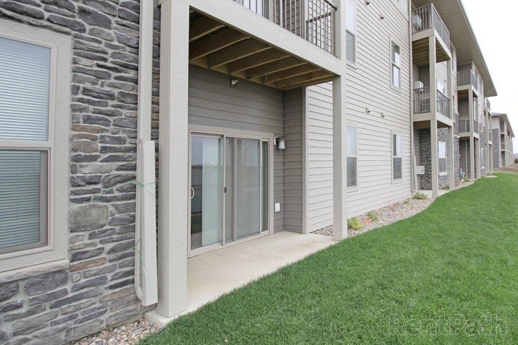 a covered walkway leading to a building with glass doors