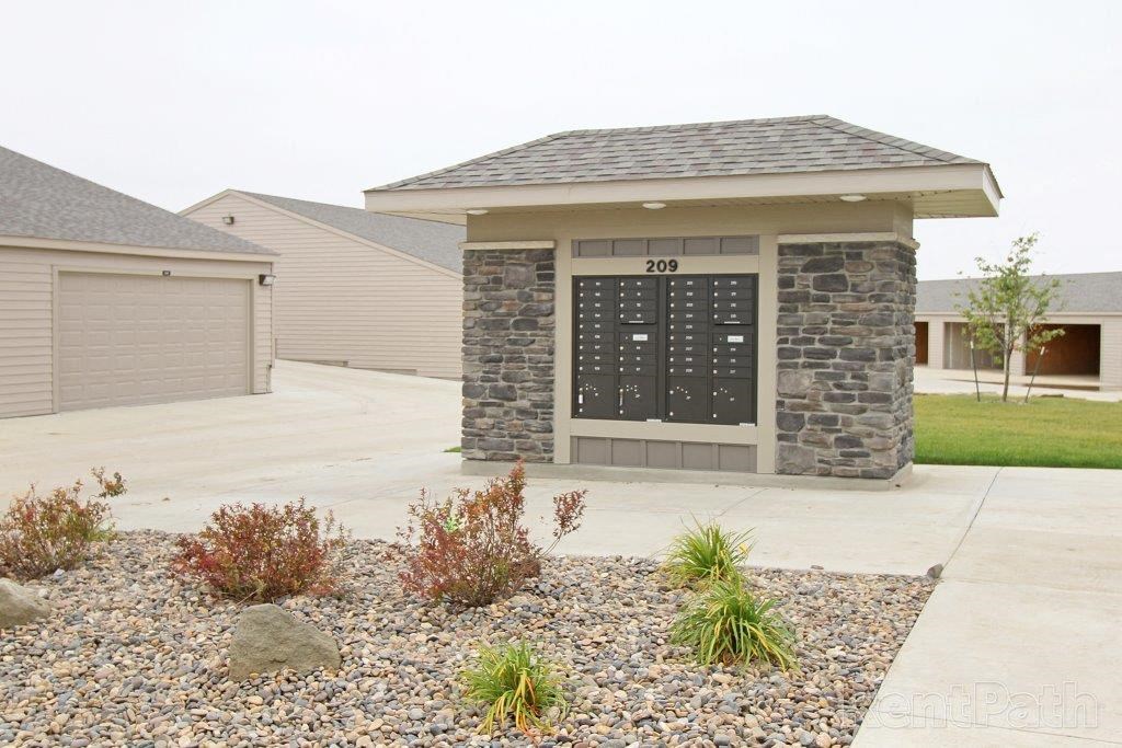 a house with a driveway and a stone building with a garage door