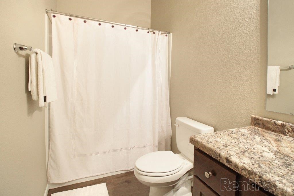 a bathroom with a white shower curtain and a toilet