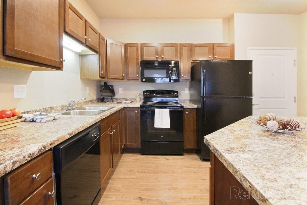 a large kitchen with wooden cabinets and black appliances