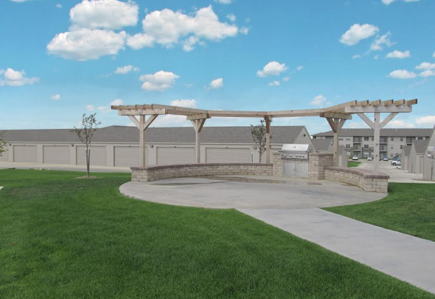 a patio with a stone wall and a pergola in front of a building