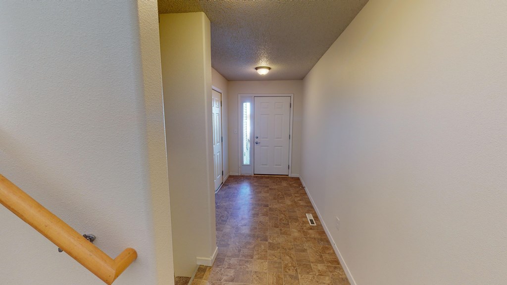 A hallway with a wooden floor and a white door at the end.