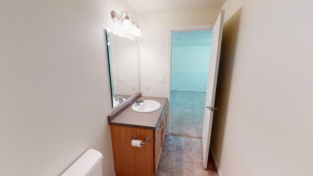 A bathroom with a sink, mirror, and toilet.