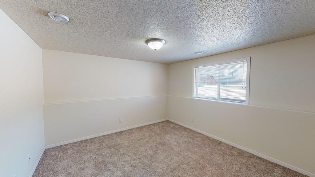 A room with a window and carpeted floor.