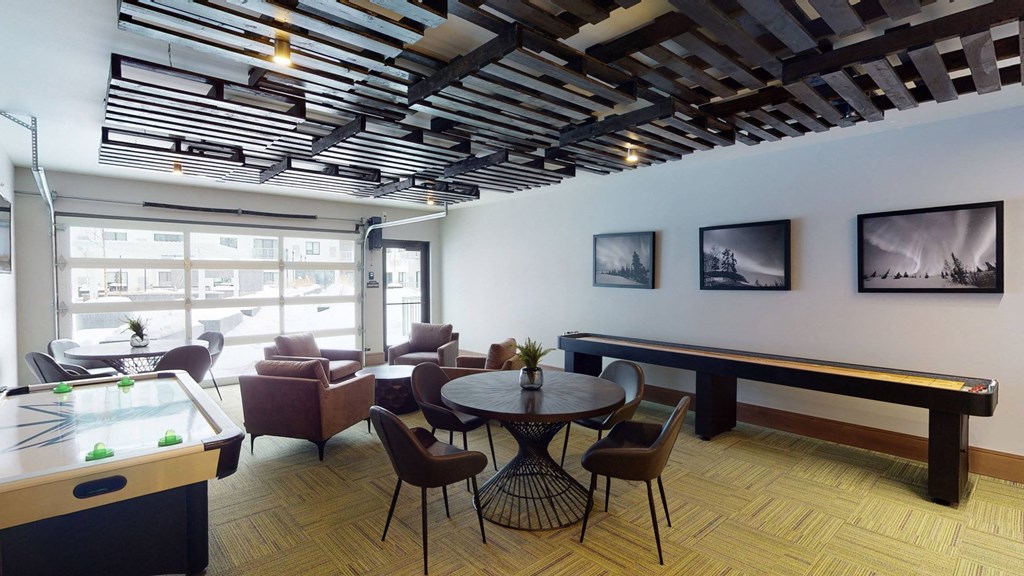 Club room with a shuffle board and chairs and a large window at Northern Lights a Lifestyle-Driven Community, West Fargo, 58078