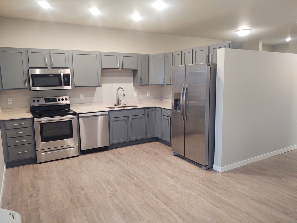 a kitchen with stainless steel appliances and gray cabinets at Northern Lights a Lifestyle-Driven Community, North Dakota, 58078