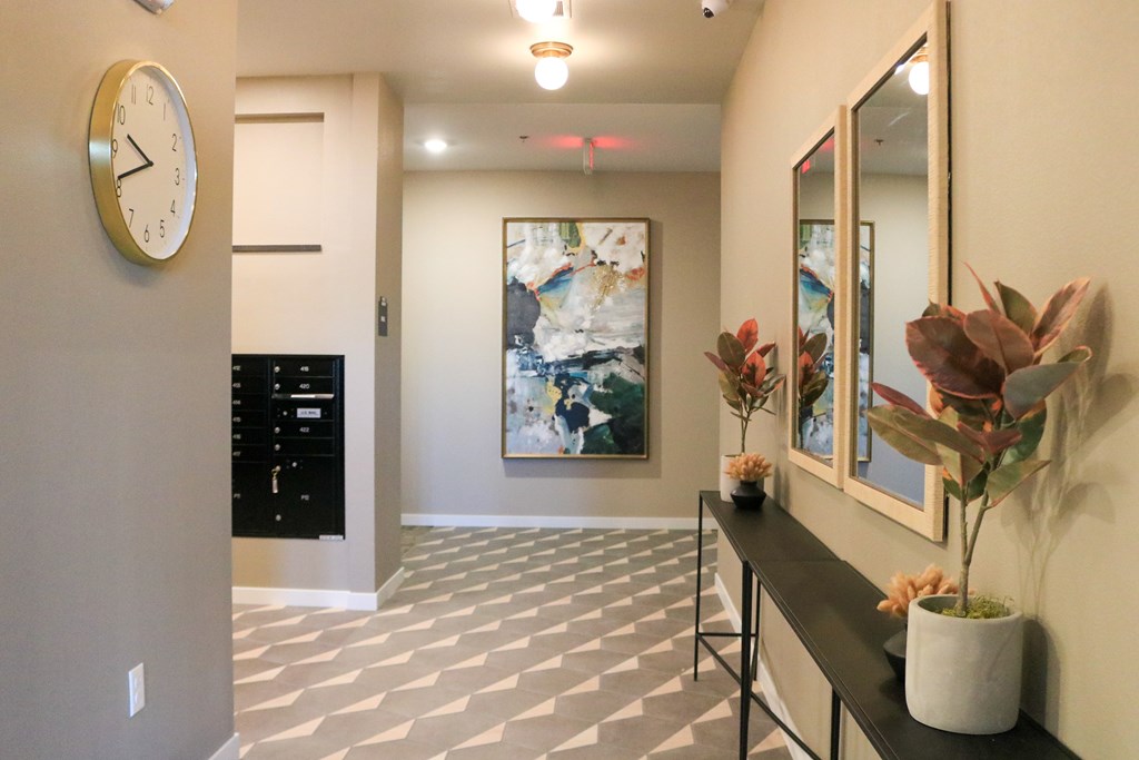 A hallway with a clock on the wall and a painting hanging above a console table.
