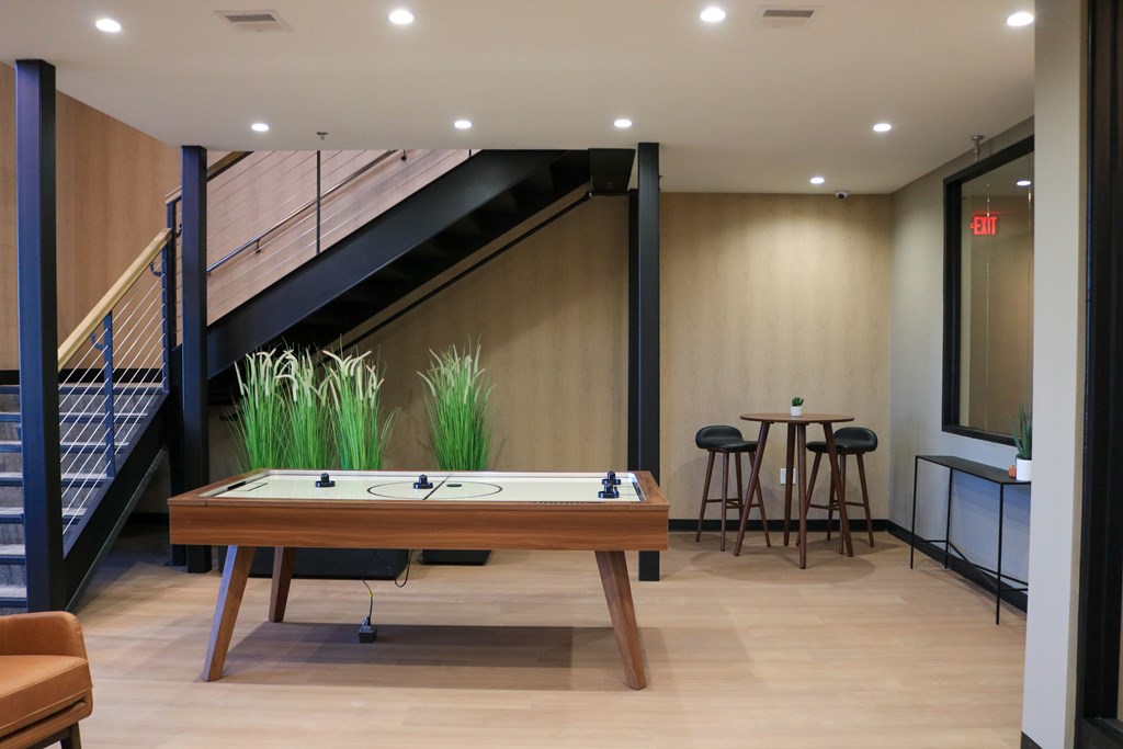 A foosball table is in the middle of a room with a staircase in the background.