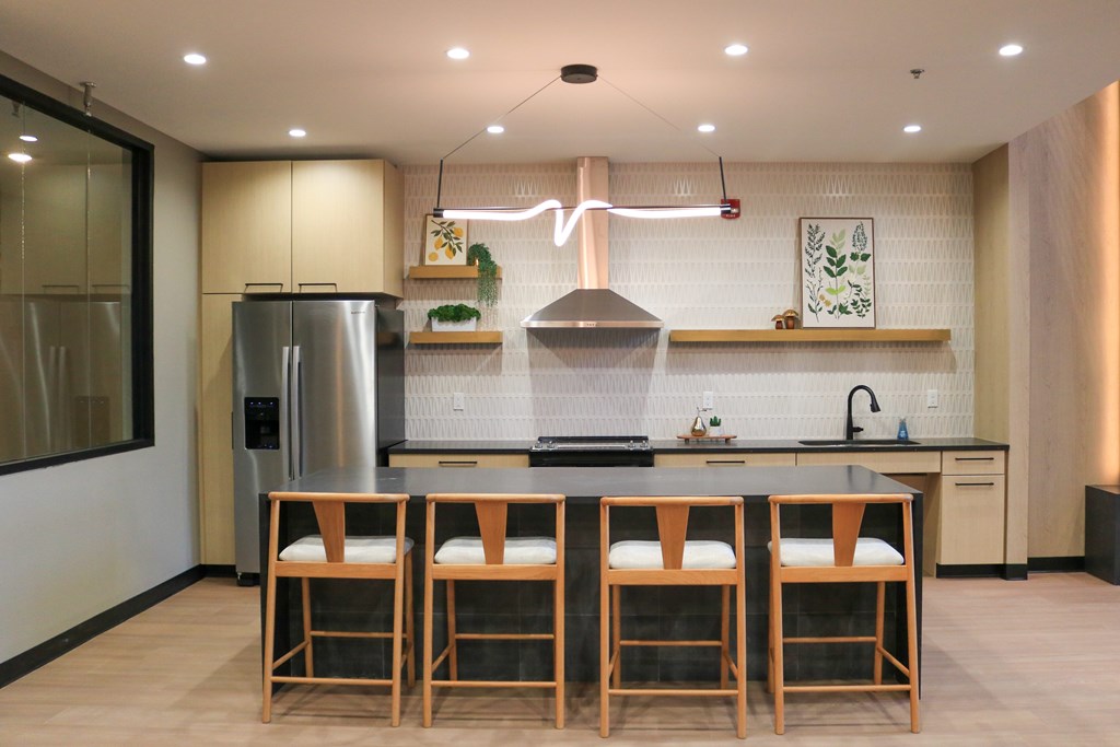 A modern kitchen with a large island and wooden chairs.
