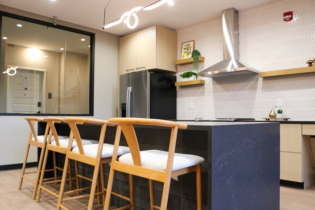 A kitchen with a black refrigerator and wooden bar stools.