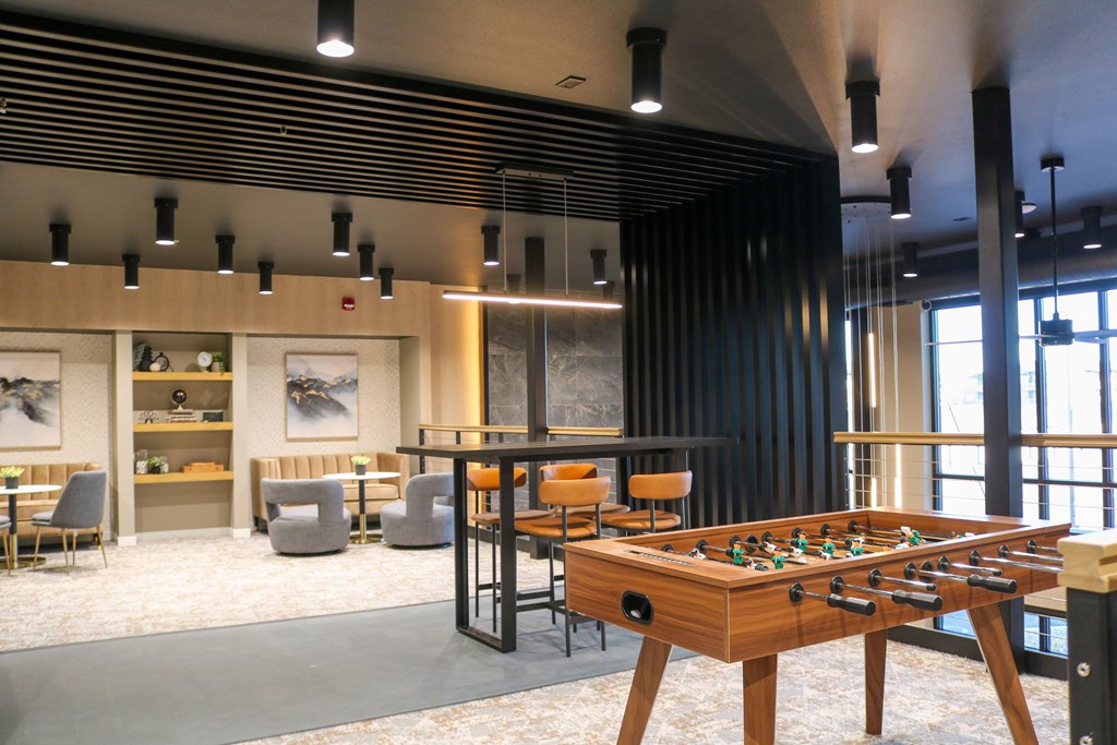 A foosball table is in the middle of a room with a black striped wall behind it.