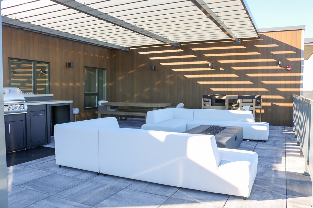 A white couch is on a patio with a wooden building in the background.