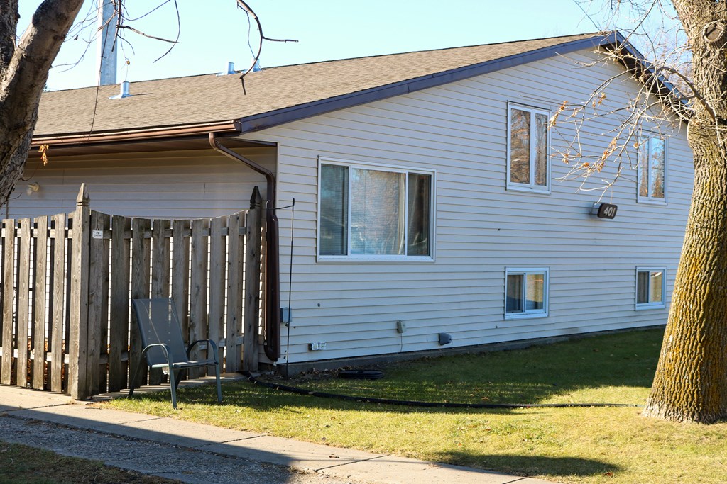 A white house with a brown roof and a grey chair in front of it.