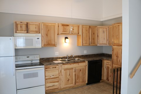 A kitchen with wooden cabinets and a black dishwasher.