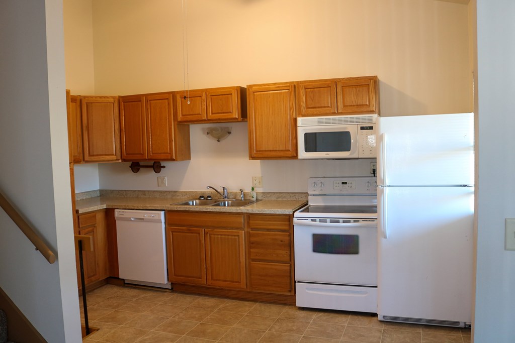 A kitchen with white appliances and wooden cabinets.