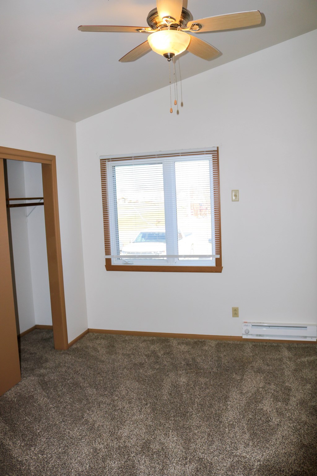 A room with a ceiling fan and a window with blinds.