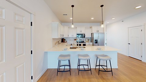 A kitchen with white cabinets and a white island with three bar stools.