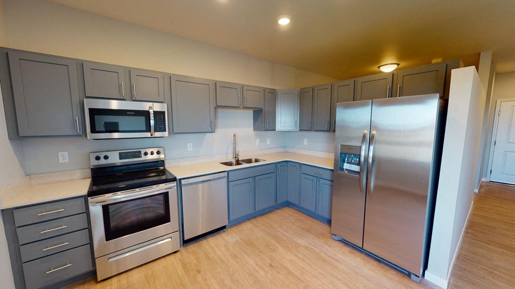 a kitchen with stainless steel appliances and blue cabinets at Northern Lights a Lifestyle-Driven Community, West Fargo, ND, 58078