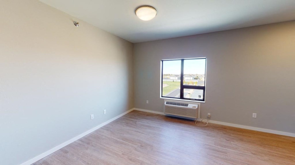 an empty living room with a window and wood floors at Northern Lights a Lifestyle-Driven Community, West Fargo, ND