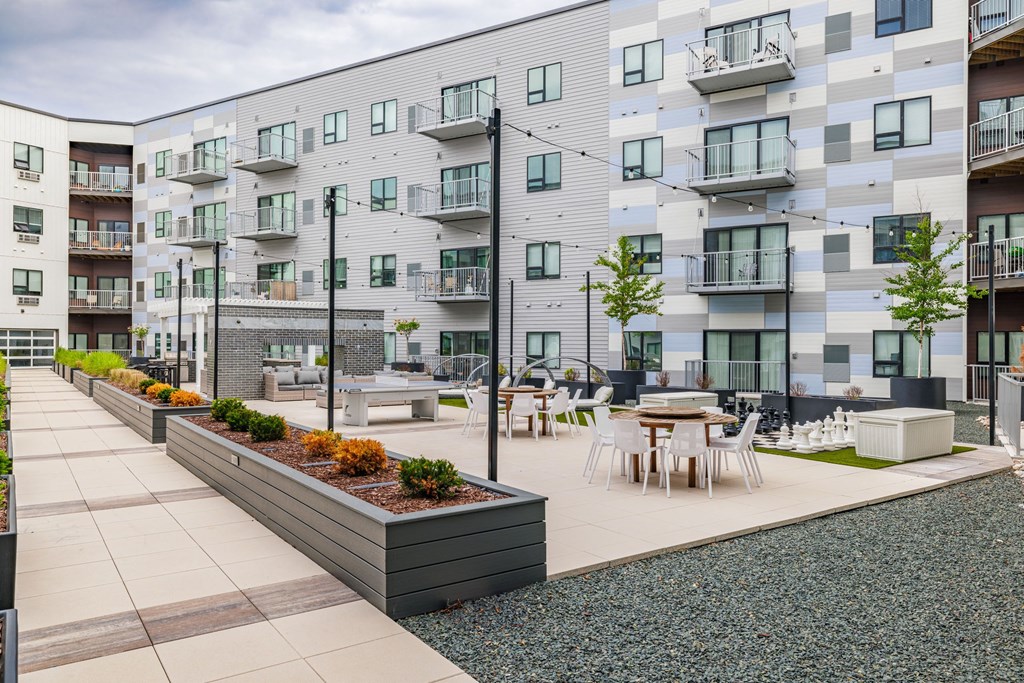 an open courtyard with tables and chairs in front of an apartment buildingat Northern Lights a Lifestyle-Driven Community, West Fargo, 58078