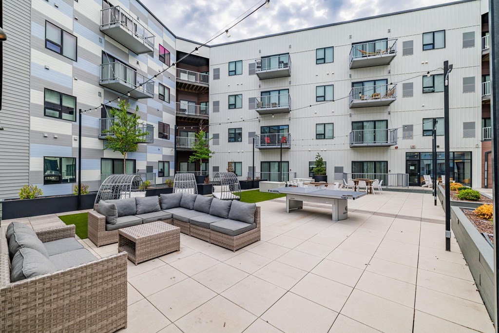 an open courtyard with couches and tables in front of an apartment building Northern Lights a Lifestyle-Driven Community, West Fargo, 58078