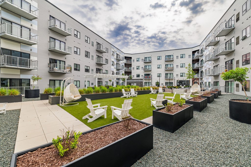 an open courtyard with chairs and tables in front of an apartment buildingat Northern Lights a Lifestyle-Driven Community, West Fargo, 58078