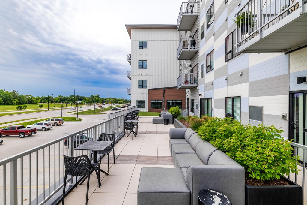 the terrace of a building with tables and chairs and a balconyat Northern Lights a Lifestyle-Driven Community, West Fargo, 58078