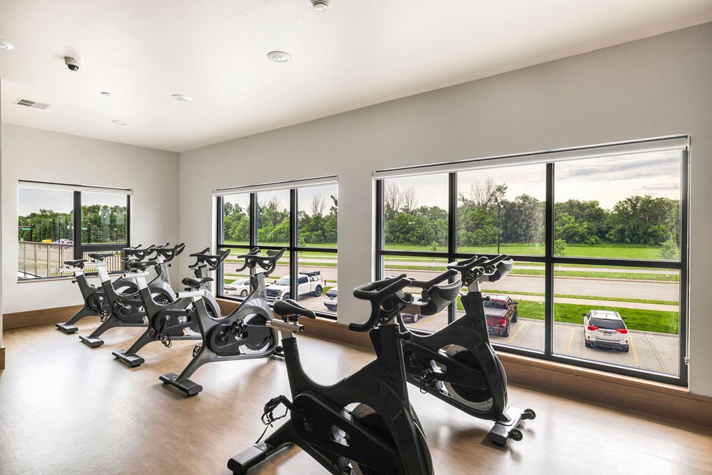 a gym with a row of exercise bikes in front of windows at Northern Lights a Lifestyle-Driven Community, West Fargo, 58078