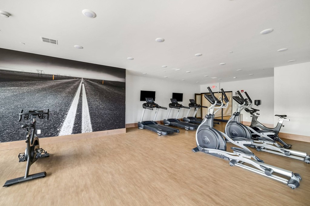 a gym with treadmills and dumbbells on a wood floor at Northern Lights a Lifestyle-Driven Community, West Fargo, North Dakota