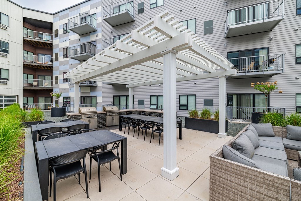 a patio with tables and chairs and a white pergolaat Northern Lights a Lifestyle-Driven Community, North Dakota