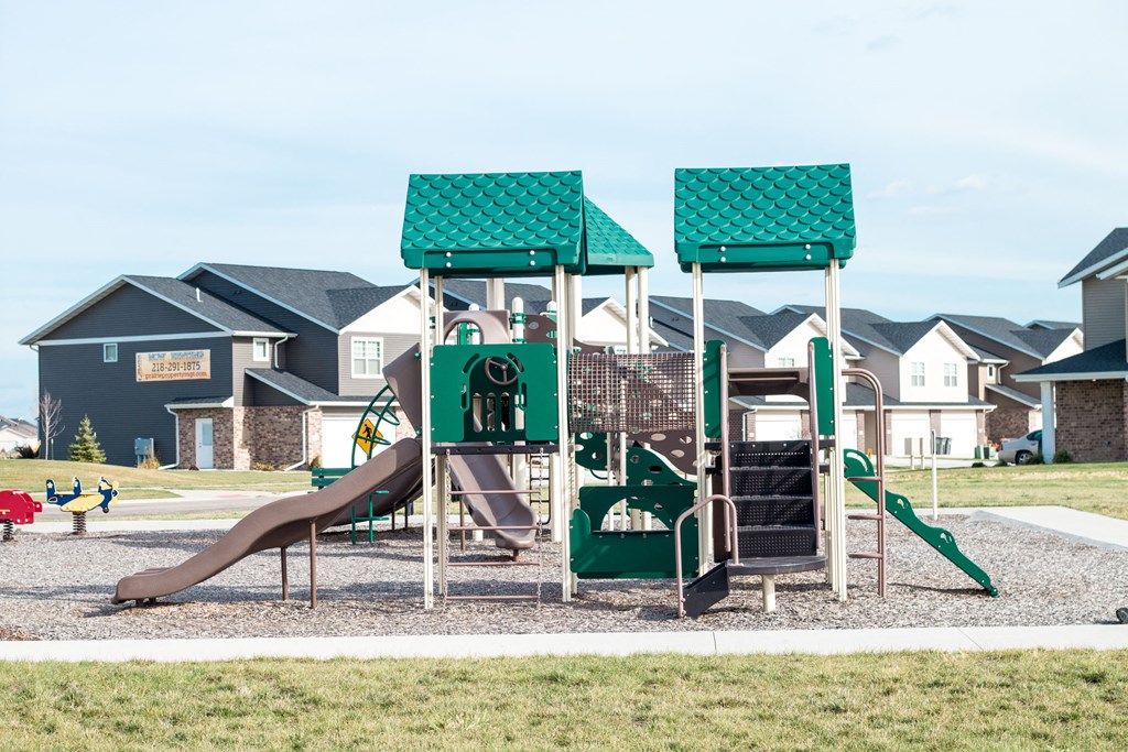 A playground with a green slide and a brown slide.