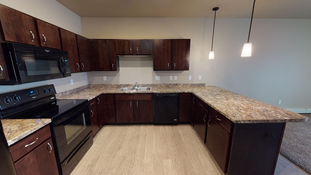 A kitchen with dark brown cabinets and granite countertops.