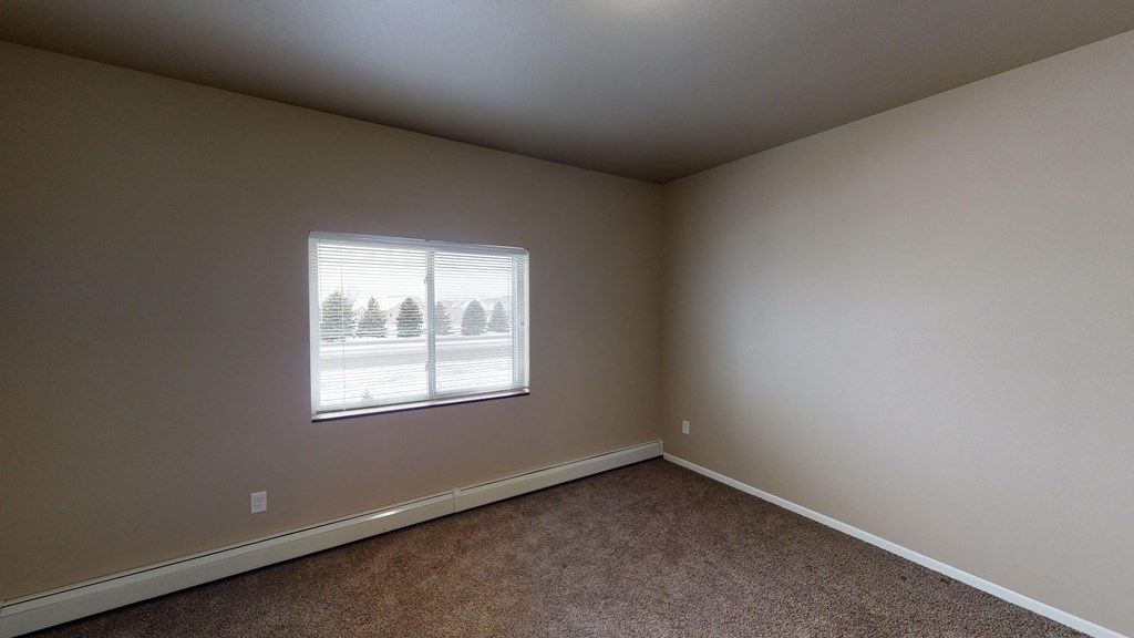 A room with a window showing a view of trees and a building outside.