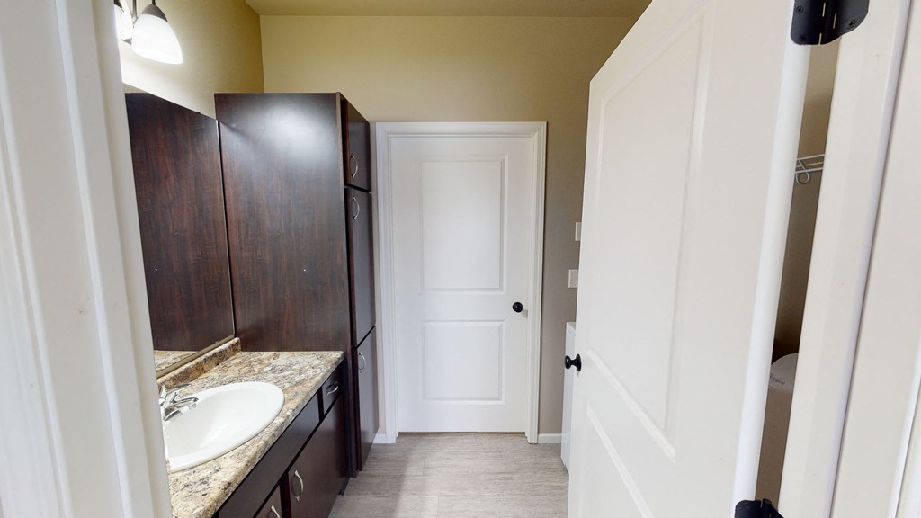 A bathroom with a sink, mirror, and cabinets.