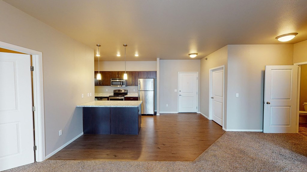 A kitchen with a refrigerator, sink, and cabinets is visible from the living room.
