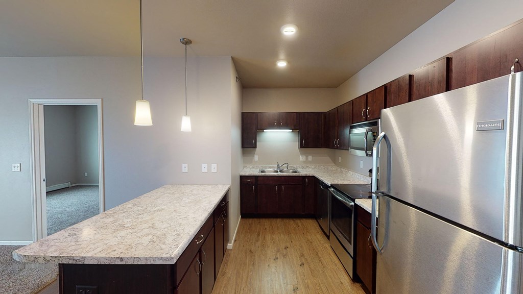 A kitchen with a refrigerator, microwave, and oven.