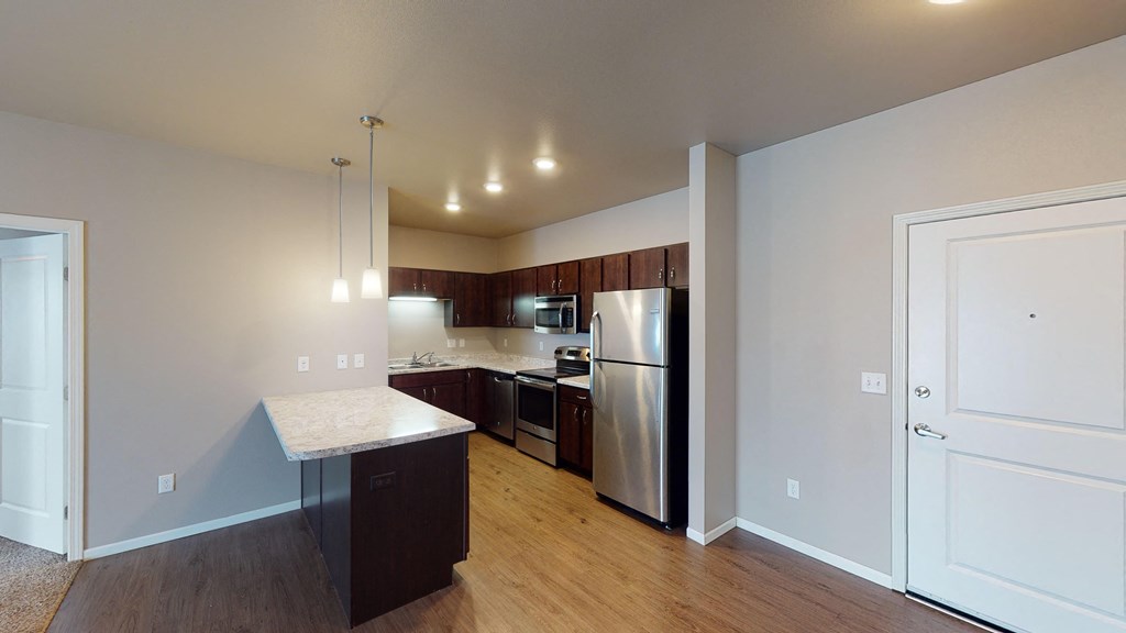 A kitchen with a refrigerator, oven, and sink.