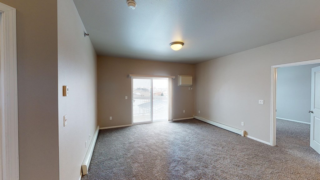 A spacious room with a carpeted floor and a ceiling fan.