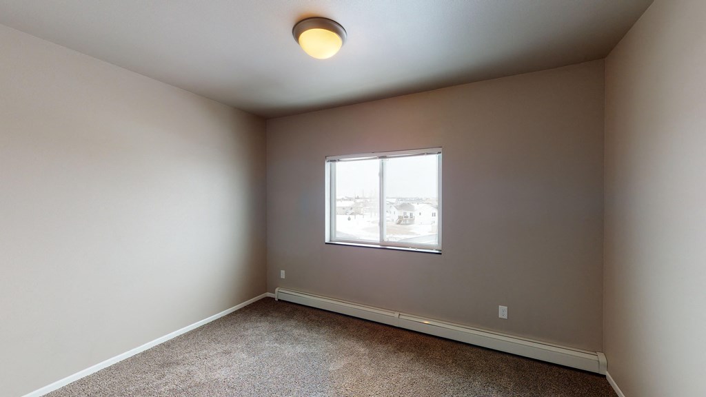 A room with a carpeted floor and a window.