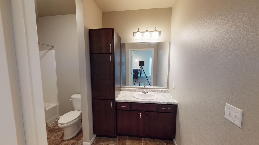 A bathroom with a toilet, sink, and a large mirror.